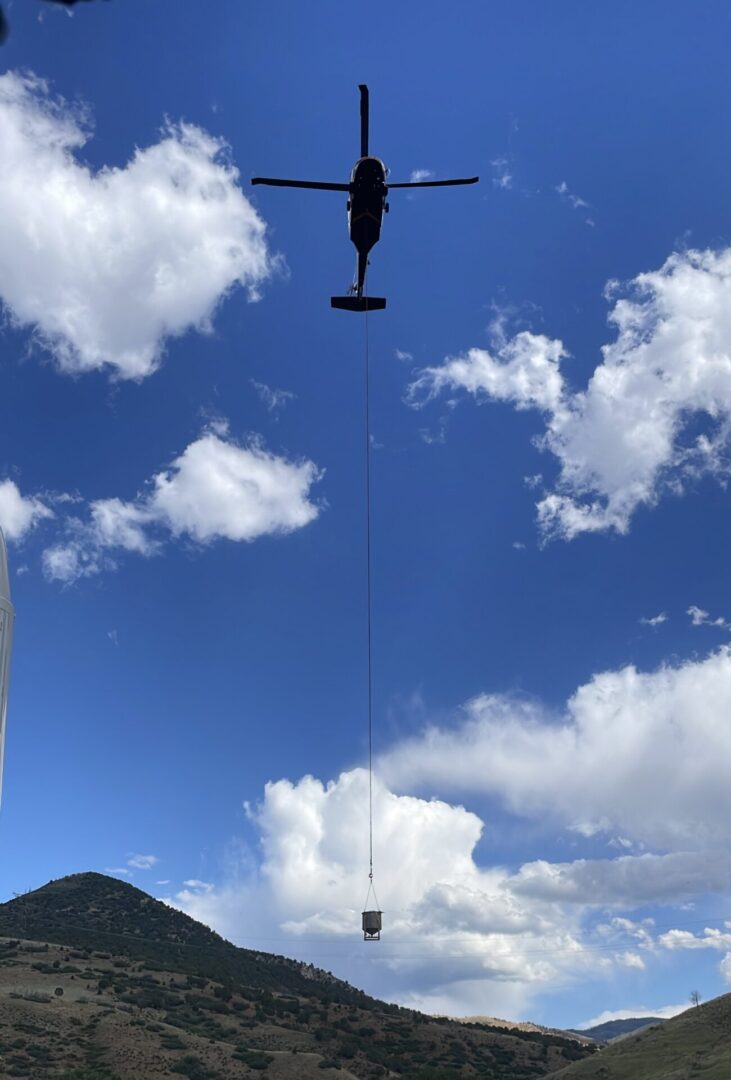 A helicopter flying in the sky with a rope attached to it.